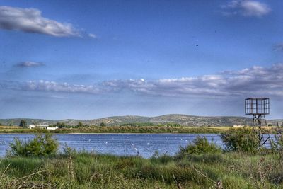 Scenic view of field by lake against sky
