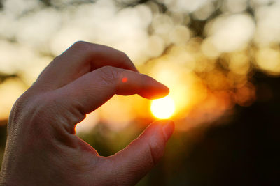 Optical illusion of hand holding sun during sunset