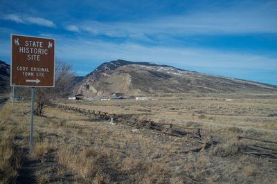 Information sign on field by mountain against sky