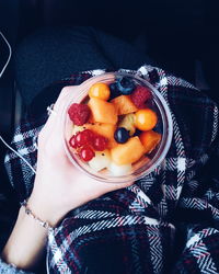 Cropped image of woman holding various fruits in glass container