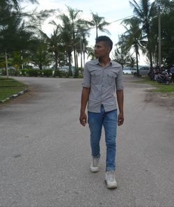 Portrait of young man standing on footpath