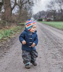 Full length of cute girl wearing warm clothing while standing on road