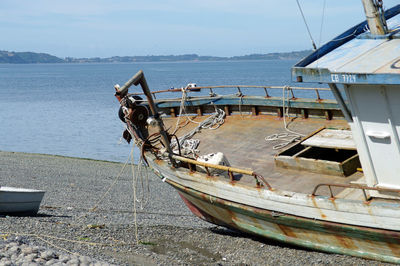 Boat moored on beach against sky