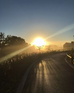 Empty road against sun during sunrise