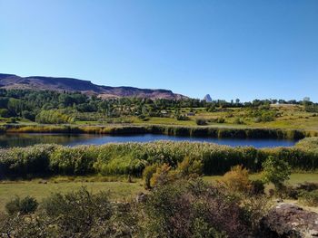 Scenic view of lake and landscape against clear sky