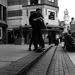Rear view of men walking on street against buildings