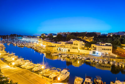 High angle view of illuminated buildings by river against blue sky