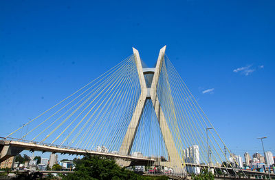 Low angle view of suspension bridge against blue sky