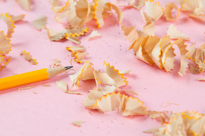 High angle view of pencil with shavings on pink background