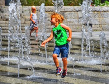 Siblings playing with water at fountain