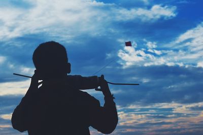 Boy flying kite against sky