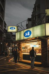 Rear view of people walking on road in city