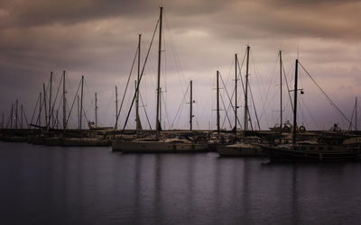 Sailboats moored at harbor against sky