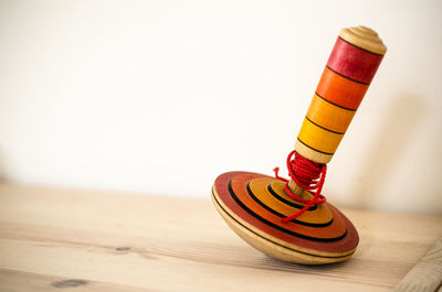 Close-up of spinning top on table against white wall