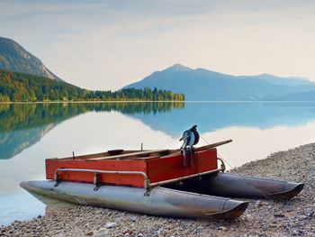 Abandoned red gray fishing boat on bank of alpine lake. autumnal morning at lake.