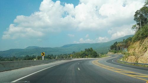 View of road and mountains against cloudy sky