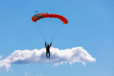 Low angle view of person paragliding against blue sky