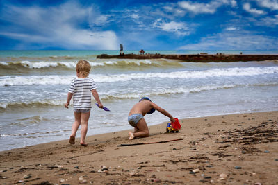 Full length of children on beach against sky