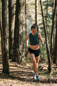 Young woman in sportswear enjoy trail running and working out in the forest