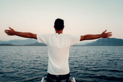 Rear view of man standing by sea against sky