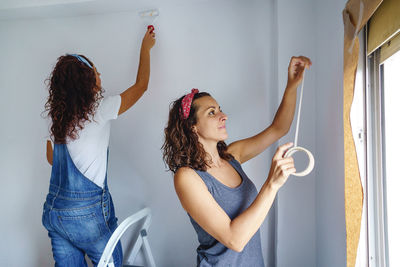 Women working while standing against wall at home