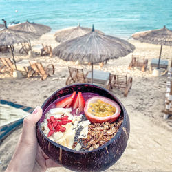 Midsection of person holding ice cream on beach