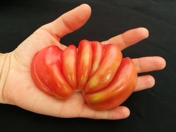 High angle view of hand holding orange over black background