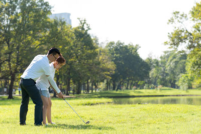 Full length of couple playing golf on field