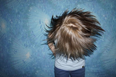 Close-up of woman with tousled hair against colored background