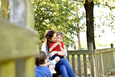 Rear view of smiling girl sitting on tree