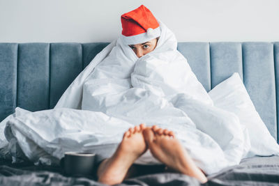 Rear view of woman wearing mask on bed at home