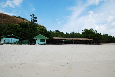 Houses on beach by trees against sky