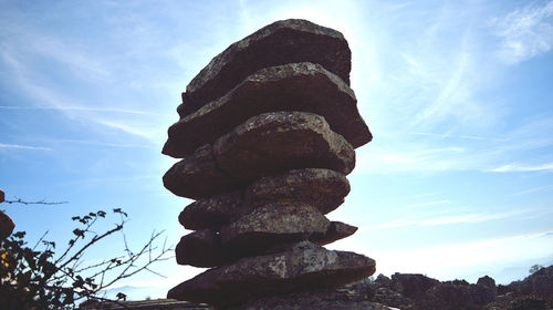 Low angle view of stone stack on rock against sky