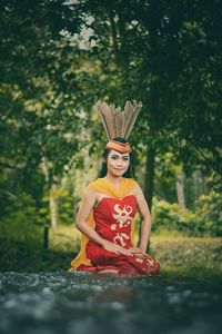 Young woman wearing traditional clothing sitting in forest