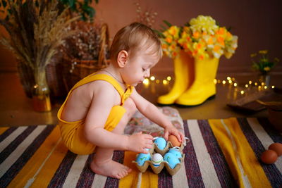 Baby with easter eggs in yellow jumpsuit