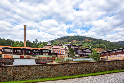 Train on railroad tracks by buildings against sky