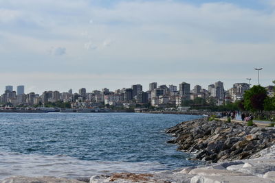 Sea by buildings against sky in city