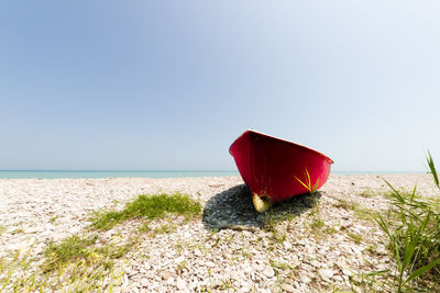 Red umbrella on beach against clear sky