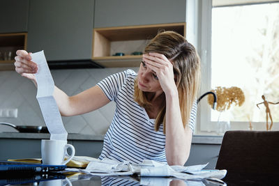 Woman calculating payment bill in kitchen