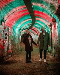 Rear view of people standing in illuminated tunnel