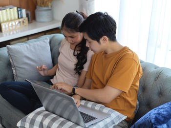 Couple using laptop while sitting at home