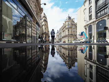 Reflection of buildings in puddle on street