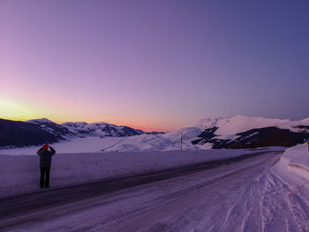 Man standing on snowy road against sky