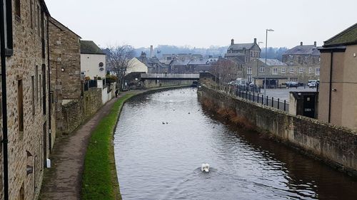 Canal amidst city against sky