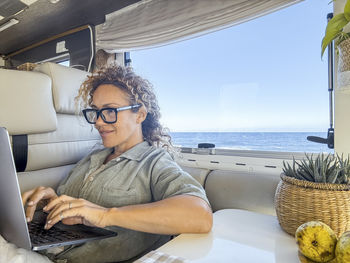 Portrait of young man using laptop while sitting in sea
