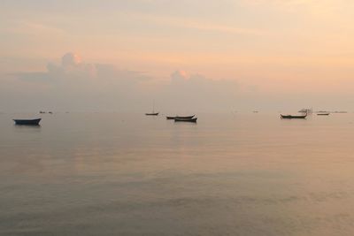 Silhouette boats in sea against sky during sunset