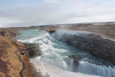 Scenic view of waterfall against sky