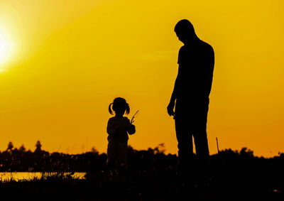 Silhouette man standing on field against sky during sunset