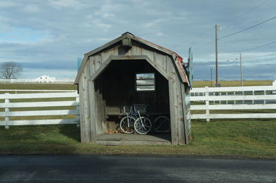 Barn on field by building against sky