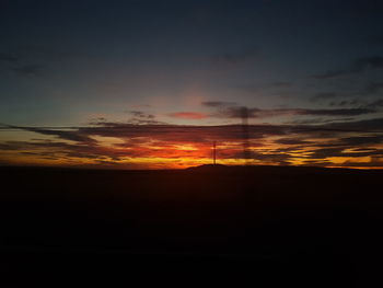 Silhouette landscape against orange sky